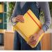 The photograph shows a stack of bright yellow lever arch files. Each file has a 50mm width and is labeled with the brand name Leitz 180° Active Cosy. The files are neatly organized and secured with a lever arch mechanism. The outer carton contains a set of 6 files. The color of the files is warm and inviting, with a glossy finish. The ACCO Brands logo is printed on the side of each file.