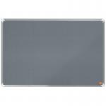 In the photo, a grey ACCO Brands Noticeboards Nobo Premium Plus Felt Notice Board can be seen. The board measures 900x600mm and is made from high-quality felt material. The surface is soft to the touch and has a textured appearance. A sleek, modern frame surrounds the board, adding to its professional look. Pins and other notes can be easily attached and removed from the board. The overall appearance is clean, tidy, and perfect for any workplace.