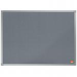 The photo displays a sleek grey ACCO Brands Noticeboards Nobo Essence Felt Notice Board, measuring 600x450mm. The soft, felt material covers the entire surface, creating a smooth and inviting texture. The edges are neatly lined with a thin, silver frame, giving the board a polished and modern look. Various notes and reminders are pinned onto the board, showcasing its spacious and practical size. The subtle grey color enhances the overall appearance, making it a stylish addition to any workspace.