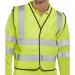 The photograph shows a group of Beeswift high visibility vests, specifically the short waistcoat app G Saturn in bright yellow. The vests are size 2XL and have the WCENGSHXXL label. They are hanging neatly, ready to be used for safety and visibility in various work environments. The fabric appears sturdy and reflective, with the Beeswift logo prominently displayed. The vests are designed to keep wearers visible and safe on the job site.