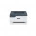 The photograph features a Xerox C230 A4 colour laser printer in its original packaging. The printer is a compact size and has a sleek white and blue design. The Xerox logo is prominently displayed on the front. Various ports and buttons can be seen on the sides.