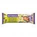 Image shows a wrapped Buttermilk Plant Powered peanut nougat caramel bar beside a cut-open piece. Cream-and-brown wrapper rests next to a glossy chocolate-coated bar, revealing sticky caramel, pale nougat layers and scattered roasted peanuts.