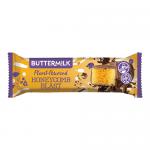 A glossy chocolate bar wrapper sits against a neutral background, displaying an image of a honeycomb-textured chocolate square with visible crunchy honeycomb pieces and creamy buttermilk swirls. Bright, playful typography and plant-powered icons punctuate the packaging. A bite shows golden honeycomb.