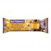 A glossy chocolate bar wrapper sits against a neutral background, displaying an image of a honeycomb-textured chocolate square with visible crunchy honeycomb pieces and creamy buttermilk swirls. Bright, playful typography and plant-powered icons punctuate the packaging. A bite shows golden honeycomb.