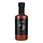 A photo shows six slender 200ml glass bottles filled with vivid red-orange sauce. Each bottle bears a bold Chilli No. 5 label with Spanish-style graphics, chili and tomato illustrations, and a black screw cap. Bottles stand aligned on a neutral background. Soft studio lighting casts dappled shadows.