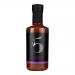 A row of six slender 200ml glass bottles holds deep red harissa, light catching oily flecks. Each bottle wears a black screw cap and a cream label with bold red script and small chilli illustrations. Condiment elements and subtle texture of the paste show through the glass. Soft studio lighting warms
