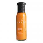 A clear glass bottle of PAYST Spicy Burnt Chilli Dipping Sauce stands upright against a pale background, revealing deep reddish-brown sauce speckled with red chilli flakes. The bold red and black label displays the brand name and product title; a metal screw cap catches light. Soft highlights gleam.