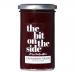 A clear glass jar holds glossy, deep-red cranberry sauce flecked with fruit pieces. A metallic screw lid caps the jar. A cream label wraps the middle, showing the brand name, a cranberry illustration and simple typography on a clean white background. The jelly glistens, hinting at chunky texture....