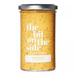 Image shows six glass jars of The Bit on the Side range are arranged on a wooden surface. Bright golden mustard with a cream label sits next to deep brown chutney jars with navy accents. Labels display the brand name and simple illustrations; metal lids reflect soft studio lighting. Subtle rim lighting.