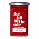 Six clear glass jars of chilli jam sit in two neat rows, revealing deep ruby-red preserves. Each jar wears a silver metal lid and a white label displaying bold black brand lettering, a small red chilli illustration and fine ingredient text. Light glints on the glossy glass.
