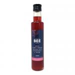 Clear glass 250ml bottle holds rosy-tinged apple cider vinegar with suspended raspberry fragments and delicate thyme sprigs. A simple label shows The Scottish Bee Company name and bee motif; natural tones and minimalist typography contrast with the bright fruit and green herb inside.