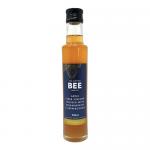 A clear 250ml glass bottle of The Scottish Bee Company apple cider vinegar stands upright, amber liquid with a pale pink tint. Its white label features strawberry and peppercorn illustrations, the brand logo and product text, topped with a silver screw-cap.