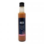 Clear 250ml bottles show a pink raspberry-hued dressing. Each bottle has a white cap and cream label with The Scottish Bee Company logo, raspberry and honey illustrations and the product name in dark type. Twelve identical bottles sit together in the pack.