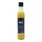A photo shows twelve 250ml bottles of The Scottish Bee Company Lemon and Honey Salad Dressing arranged in a neat grid. Translucent golden-yellow dressing fills clear bottles with white caps; labels feature the brand name, lemon and honey graphics and decorative honeycomb accents.