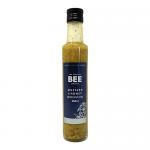A boxed pack of twelve identical 250ml bottles stands neatly arranged, each clear bottle revealing warm amber mustard-and-honey dressing. White labels feature The Scottish Bee Company logo, bee and honeycomb artwork, product name in dark type and black screw caps sit atop each bottle in kraft tray.