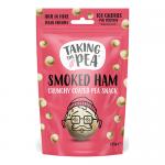 Photo shows a 125g Taking the Pea Smoked Ham sharing bag with bold logo and pink-green packaging. An illustrated ham and peas decorate the front. The torn bag lies open, spilling ridged crisps across a wooden board; seasoning flecks and texture are visible.