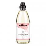 A set of six 1L translucent bottles sits grouped in two neat rows, each bottle bearing a white label with green accents and the Wilton London name. Delicate jasmine blossoms decorate the label; the pale liquid shows through and white screw caps finish each bottle. On a plain white background. Crisp.