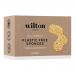 A twin pack of Wilton London eco sponges sits on a plain surface. Two compact rectangular sponges show a soft beige cellulose side and a textured green scouring layer. A recyclable paper band wraps them, displaying minimalist branding and simple product text. Soft studio lighting casts shadows. Dim.