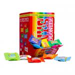 Image shows a 900g Tiny Tony’s Mix box alongside eight Tony’s Chocolonely bars scattered on a light background. Vibrant, varied wrappers—red, yellow, blue, brown—feature the bold logo. Some bars lie unwrapped, revealing irregular, chunky chocolate with visible broken pieces. Soft shadows add depth.