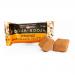 A small two-truffle pack sits against a white background, its orange-accented sleeve featuring brown lettering. Two glossy chocolate truffles rest beside the box, one halved to reveal a soft, orangey center and a smooth ganache interior dusted with cocoa.