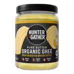 An image displays six 450g jars of Hunter & Gather grass-fed British organic ghee arranged in two rows. Transparent jars reveal smooth, pale-gold ghee. Cream labels with green accents show the Hunter & Gather logo and product name. The scene rests on a neutral surface.