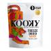 A cluster of twelve compact matte pouches in vibrant mango-orange, each labeled Kooky Freeze Dried Mango 100% Fruit 12g. A clear window shows airy, shriveled bright-orange mango pieces. A playful logo and small fruit illustrations decorate the packaging.