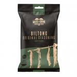 A small resealable pouch rests on a neutral surface, labeled Made for Drink. Through a clear window, dark-brown strips of grass-fed Irish beef biltong appear stacked and textured. Rustic typography, green accents and a compact 30g pack convey an artisanal, natural look. Hands reach in to lift strip.