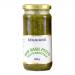 A clear glass jar of Seggiano Raw Basil Pesto shows vibrant green, coarse-textured paste with visible basil flecks and pine nut bits, a glossy olive oil sheen on top, and a branded green-and-white label beneath a metal screw lid.