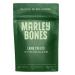A bright pouch labeled Marleybones sits beside five identical packs, each showing a photo of sliced lamb and green superfood icons. The bag has a clear window revealing small, amber-brown air-dried bites; a bold white logo, red accents, and ingredient illustrations frame the layout Soft shadows lie