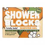 A bright lifestyle shot shows six round solid shower blocks stacked and scattered on a white marble surface, their orange hues and speckled textures catching soft morning light. Fresh bergamot leaves and sliced orange halves sit nearby, while water droplets add a dewy sheen and tiny glints of light.