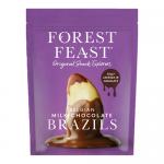 Image shows a glossy Belgian milk chocolate slab studded with whole Brazil nuts and a scatter of dried fruits, nuts and seeds. Pieces sit on a textured wooden board beside a minimalist wrapper bearing Forest Feast branding.