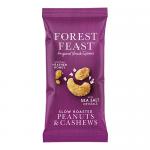 A small impulse-size Forest Feast packet sits on a rustic wooden surface. The colorful wrapper shows slow-roasted peanuts and cashews imagery. Shelled peanuts, cashews, sunflower seeds and dried fruit spill around the pack, creating a casual, natural arrangement. Soft highlights emphasize nutty sheen.