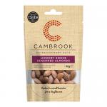 A glossy Cambrook packet of Hickory Smoke Seasoned Almonds fills the frame. The dark amber packaging shows a bold Cambrook logo and the product name, with a close-up of seasoned almonds piled in front, smoky wisps and contrasting orange accents; a nutrition panel appears on the back. Subtle shadows.