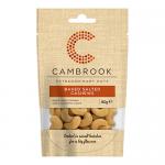 A front-facing snack pouch shows the Cambrook logo and large text reading Baked & Salted Cashews. Warm orange and cream graphics frame a photo of whole cashews, while a clear window reveals pale roasted nuts packed inside.