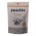 A clear glass jar with a peach-toned label sits against a neutral background. The lid gleams; inside a crunchy mix of hazelnut pieces, cacao nibs, dried cherry bits and mixed seeds creates a textured, earthy palette of browns, deep reds and cream hues, with visible crumbs and flakes. Soft highlights.