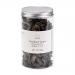 A clear plastic pouch displays irregular, glossy black fungus pieces—thin, ruffled, ear-like shapes with wrinkled, dark surfaces. A simple white label shows the Emma Basic brand and product details; the pouch rests against a plain, light background. Soft light reveals glossy sheen and delicate edges