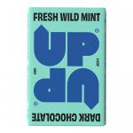 Photo shows stacked UP-UP Dark Wild Mint bars beside UP-UP Chocolate packs. Matte dark wrappers with mint-green accents and leaf motifs sit next to warm brown chocolate packaging. Items rest on a neutral surface with soft light and crisp, gentle shadows.