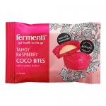 The photo shows a neat row of individually wrapped raspberry-coconut bites scattered beside an open box. Each 12g bar displays a pastel wrapper with berry and coconut illustrations; one bite is unwrapped to reveal a glossy cashew-fondant center and textured coconut coating. Soft light shows texture.