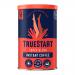 A small clear jar of TrueStart Super Blend Instant Coffee sits on a grocery shelf. The label shows bold TrueStart lettering over dark brown and gold graphics with a steaming cup illustration. Golden-brown granules are visible through the glass jar.
