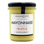 Close-up of several glass jars of Charlie & Ivy’s Truffle Mayonnaise, creamy pale spread visible through clear glass and sealed with black lids and gold foil accents. Jars sit on a rustic wooden board surrounded by pine sprigs, cinnamon sticks, cranberries and warm, soft-focus holiday lights. aglow.