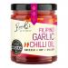 A clear glass bottle holds bright orange-red garlic chili oil studded with thin fried garlic slices and red chili flakes. A simple label shows RoniB's Kitchen logo and Filipino‑style text; light catches the glossy oil, highlighting suspended spices and a subtle shimmering surface. Soft light glows..