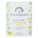 A small rectangular box sits on a neutral background. Soft yellow panels carry scattered chamomile illustrations and green leaves. A red emblem appears near the top, while bold serif text displays the brand and product name. Clean, simple packaging and a soothing color palette. Matte finish. Subtle.