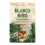 A bright bag shows the Blanco Niño logo atop a creamy jalapeño graphic. Golden, triangular tortilla chips spill from the package, speckled with seasoning. Fresh jalapeño slices and a swirl of pale green dip accent the vibrant, snack-focused composition. Soft studio light and pale teal backdrop glow.