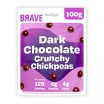 Photo shows six 100g packs of Brave Roasted Chickpeas Dark Chocolate arranged in a fan on a neutral surface. Glossy dark-brown wrappers display close-up images of chocolate-coated chickpeas, a handful of real roasted chickpeas, and bold white brand lettering. Soft studio lighting casts subtle shadow