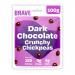 Photo shows six 100g packs of Brave Roasted Chickpeas Dark Chocolate arranged in a fan on a neutral surface. Glossy dark-brown wrappers display close-up images of chocolate-coated chickpeas, a handful of real roasted chickpeas, and bold white brand lettering. Soft studio lighting casts subtle shadow