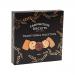 Photo shows a black rectangular selection box with gold serif lettering and a vintage bakery crest. A transparent window reveals eight assorted golden-brown biscuits arranged on parchment. The box rests on a rustic wooden surface beside sprigs of wheat and a folded linen. Soft warm glow brings out grain.