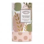 A cylindrical tube sits upright beside a neat stack of round biscuits, each half-dipped in glossy milk chocolate and sprinkled with oat crumbles. Golden-brown biscuit texture contrasts with smooth chocolate; rustic bakery logo and muted, farmhouse-inspired packaging colors complete the scene. Nearby