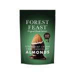 A glossy pouch displays dark chocolate-coated almonds with visible peppermint cream swirls, scattered alongside whole almonds, dried fruit and seeds. The Forest Feast logo and product name appear atop an earthy, natural-toned background. Mint-green accents and subtle seed icons line the lower edges.