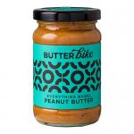 Six clear glass jars are arranged in two neat rows, each bearing a white label with 'Butter Bike Co' in bold type and an illustrated bagel. Pale, creamy peanut butter shows through, speckled with sesame and poppy seeds. Matte black lids and a simple cardboard tray complete the set. Soft reflections.