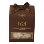 A rectangular box sits on a neutral surface, its glossy sleeve showing rich dark chocolate swirls and golden honeycomb motifs. A clear window reveals pale nougat studded with chocolate pieces. Elegant typography and subtle confectionery branding finish the design.